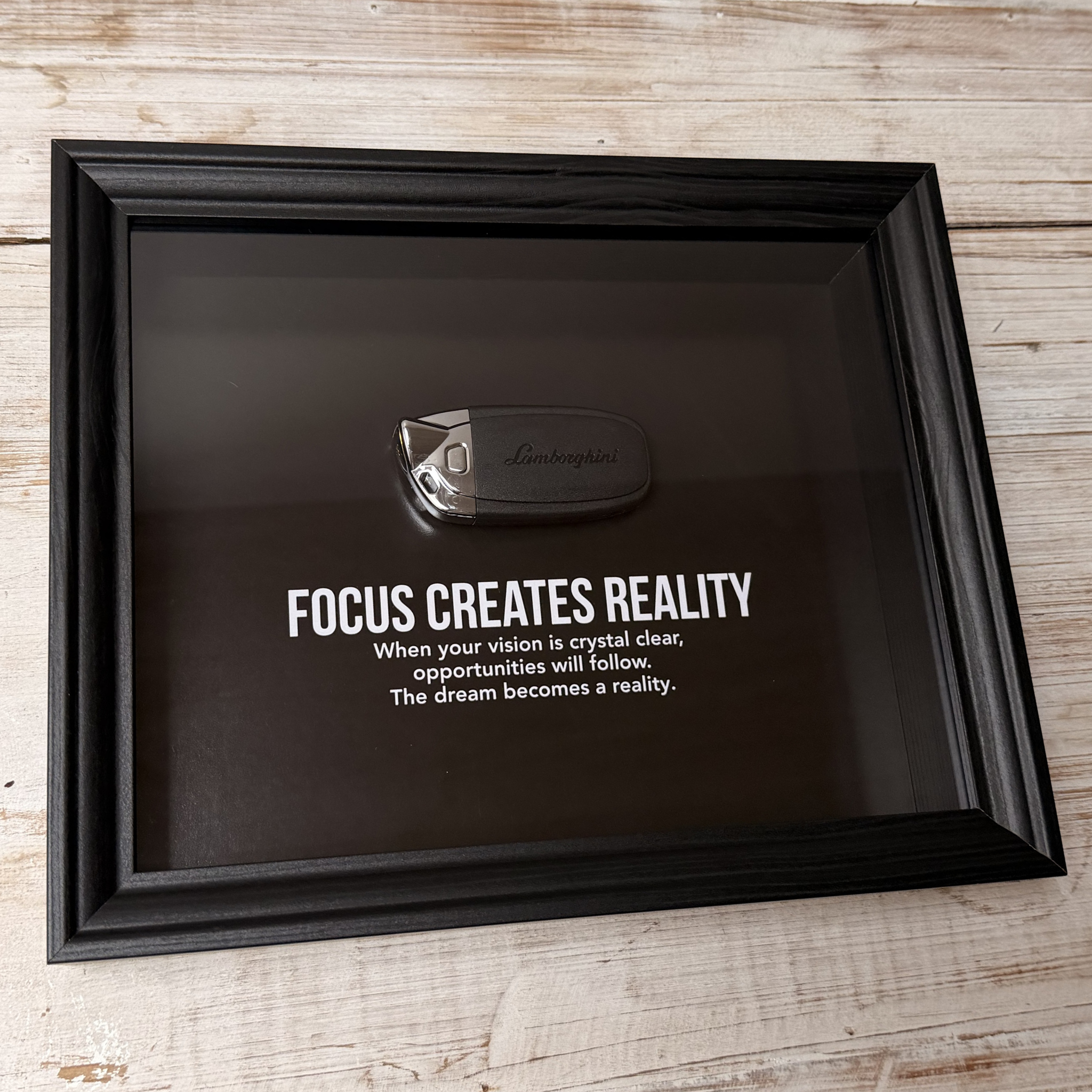 Een zwart stijlvol foto-frame met daarin een echte Lamborghini autosleutel. in het frame zien we een motivatie tekst om mensen te inspireren richting hun eigen droomwagen. 