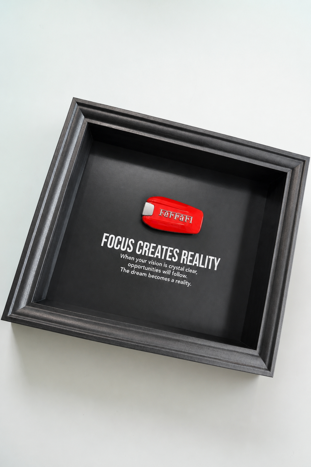Een zwart stijlvol foto-frame met daarin een echte Ferrari autosleutel. in het frame zien we een motivatie tekst om mensen te inspireren richting hun eigen droomwagen.