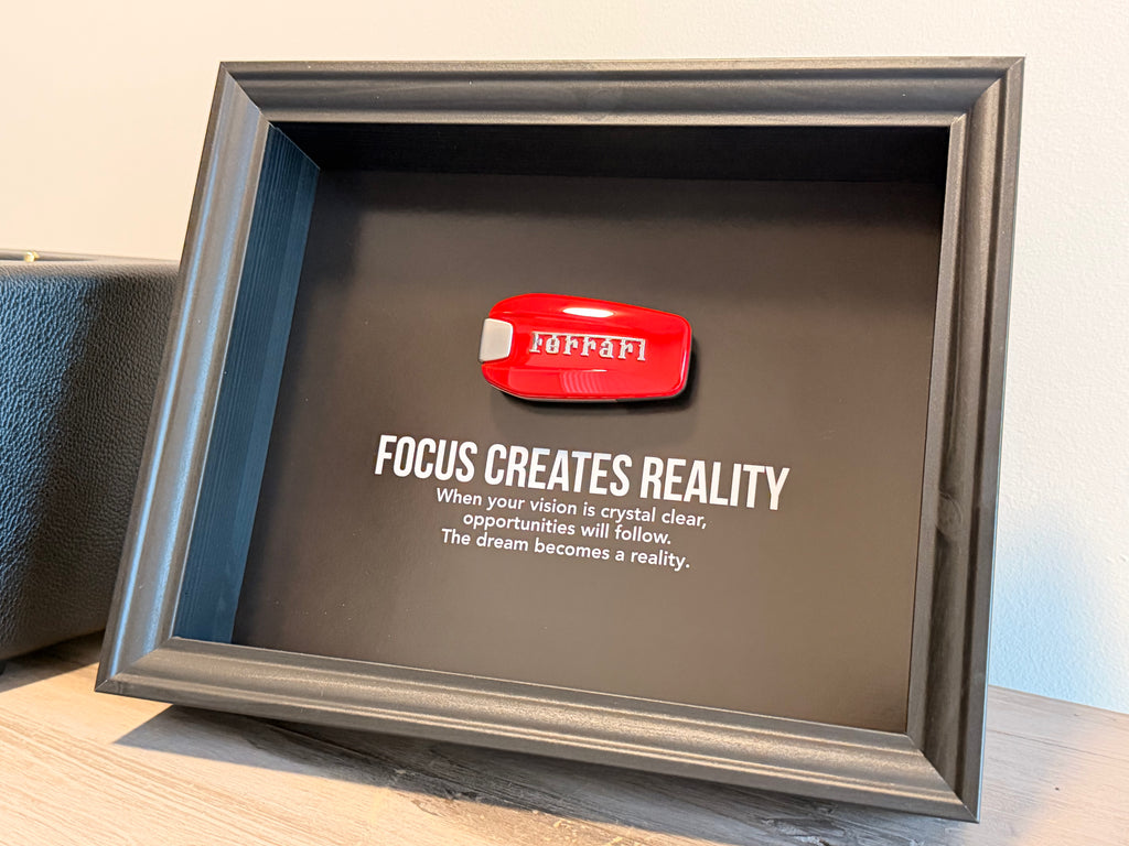 Een zwart stijlvol foto-frame met daarin een echte Ferrari autosleutel. in het frame zien we een motivatie tekst om mensen te inspireren richting hun eigen droomwagen.