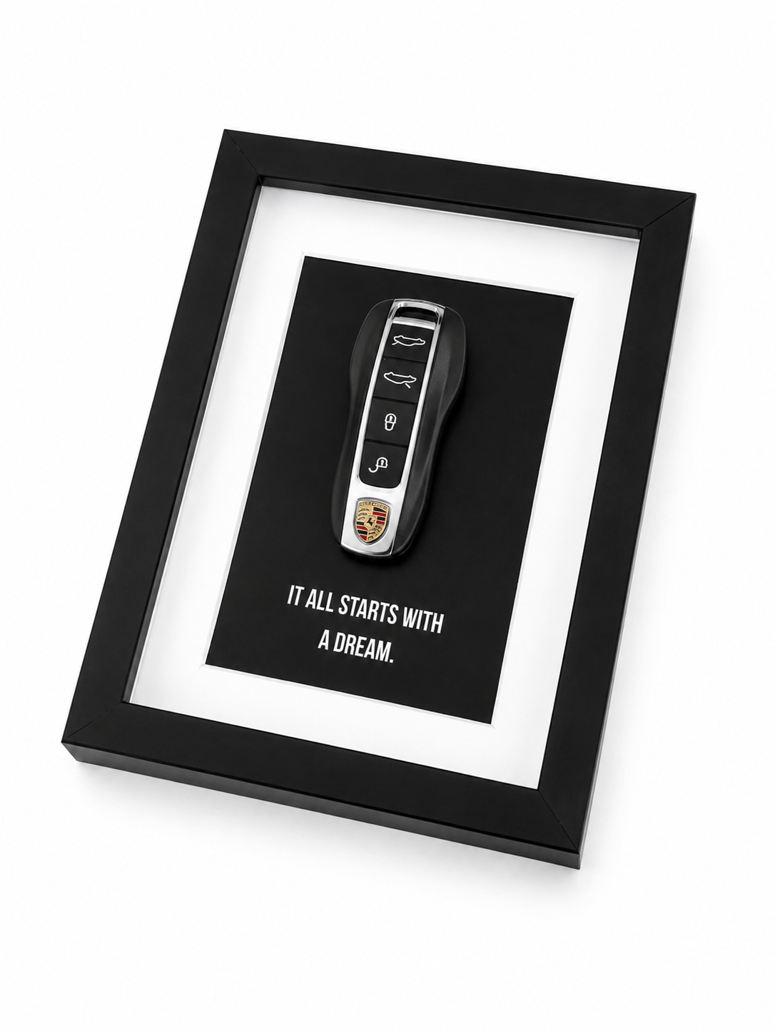 Een kader met motiverende tekst: It all starts with a dream. in de kader zit een echte porsche sleutel. 