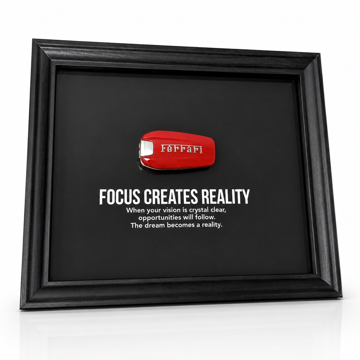 een stijlvolle zwarte kader, met een zwarte achtergrond, met een echte Ferrari sleutel. de motiverende tekst in het kader leest: Focus creates reality. 
