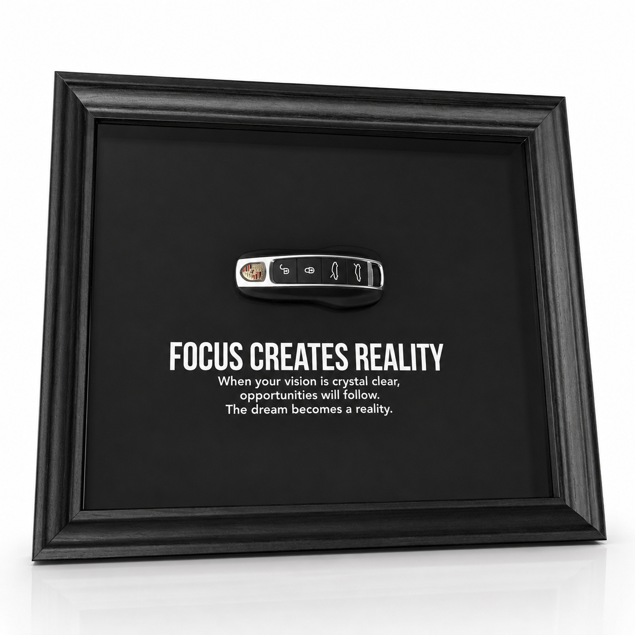 een stijlvolle zwarte kader, met een zwarte achtergrond, met een echte Porsche sleutel. de motiverende tekst in het kader leest: Focus creates reality. 