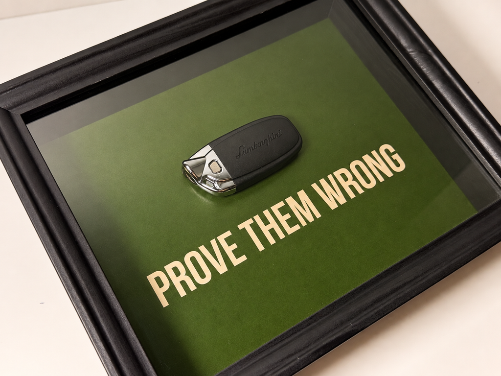 een stijlvol zwart kader met een groene achterkant, met een echte Lamborghini sleutel. de motiverende tekst in het kader leest: prove them wrong. 